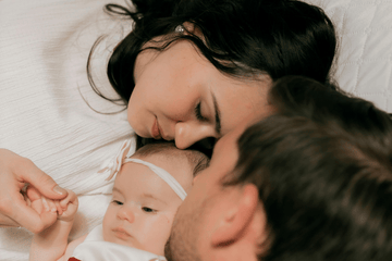 New parents resting together while supporting their newborn during the early days of parenthood