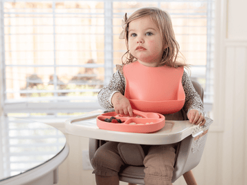 Toddler using a silicone tray, safe for microwave heating.