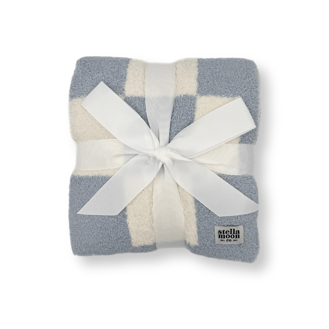 Luxe Checkered Baby Blanket in Blues wrapped with a white ribbon, showcasing its soft and cozy fabric with a serene blue checkered design – perfect for gifting.