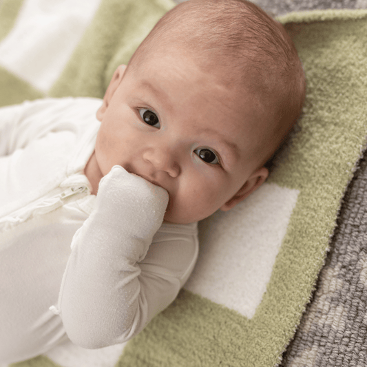 Baby resting on the Matcha Luxe Blanket, featuring a soft green and white checkered design for ultimate comfort and style.