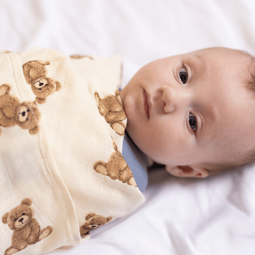 Baby swaddled in the Stella Moon Multi-Use Bamboo Swaddle in Teddy. The soft, breathable bamboo-cotton blend blanket features an adorable teddy bear print, providing warmth and comfort