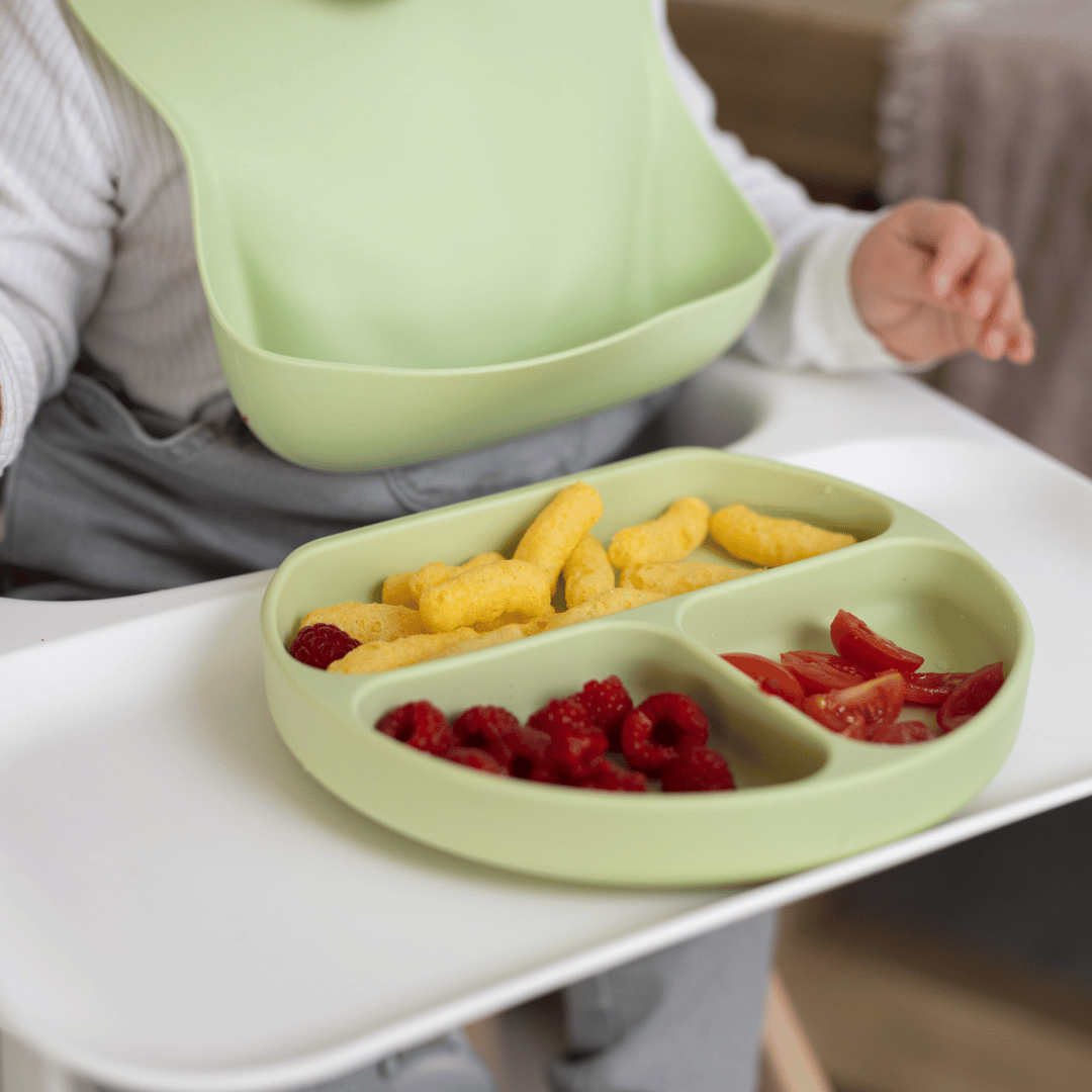 Close-up of a baby wearing the Stella Moon Silicone Bib in Spearmint while using the matching Silicone Suction Plate. BPA-free, easy to clean, and designed for mess-free meals.