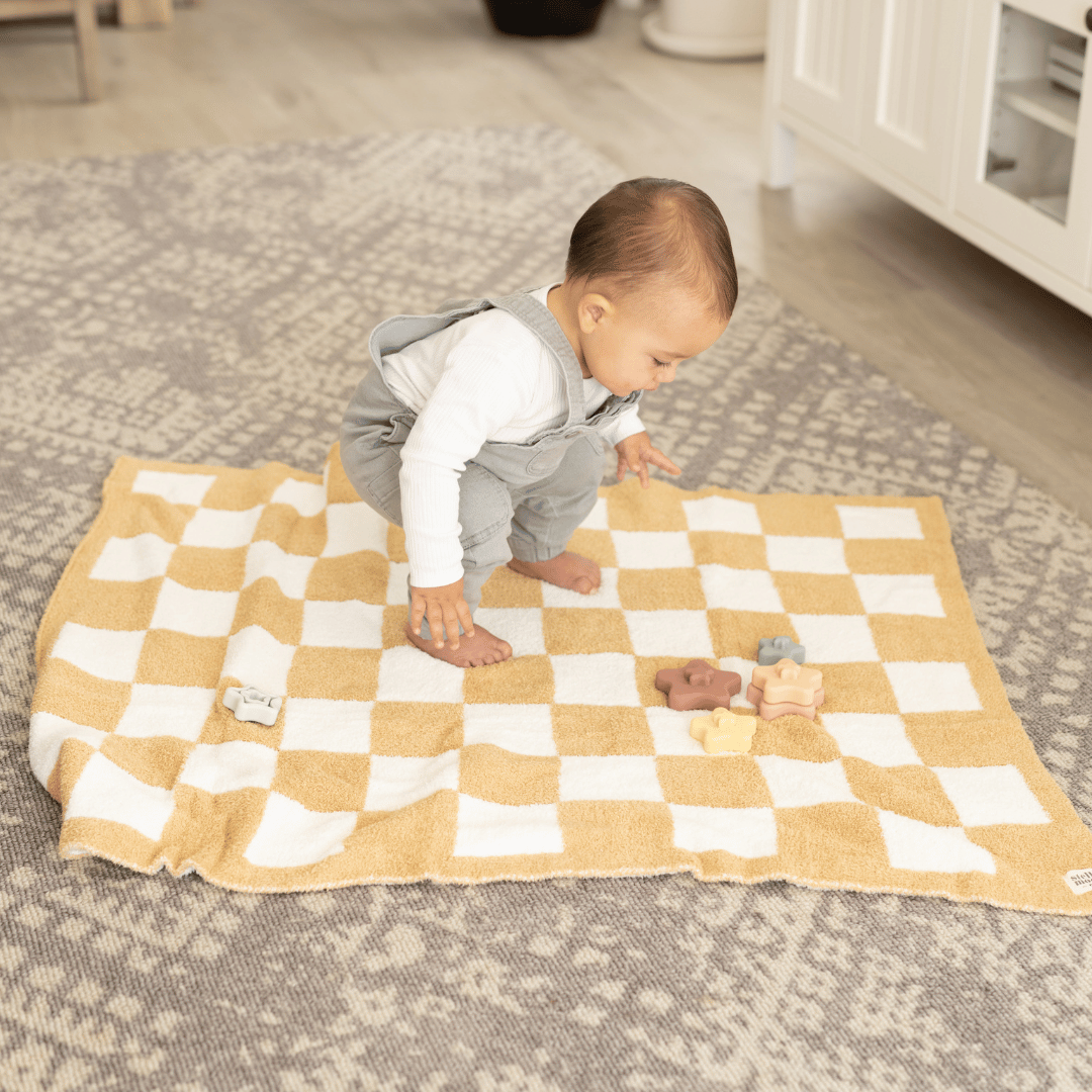 Baby playing on the Luxe Checkered Baby Blanket in Sand, highlighting its plush texture and versatile use as a play mat or nap-time essential.