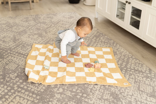 Adorable baby playing atop StellaMoon's Luxe Checkered Baby Blanket in Sand, showcasing its plush texture and generous size, perfect for playtime and cozy snuggles.