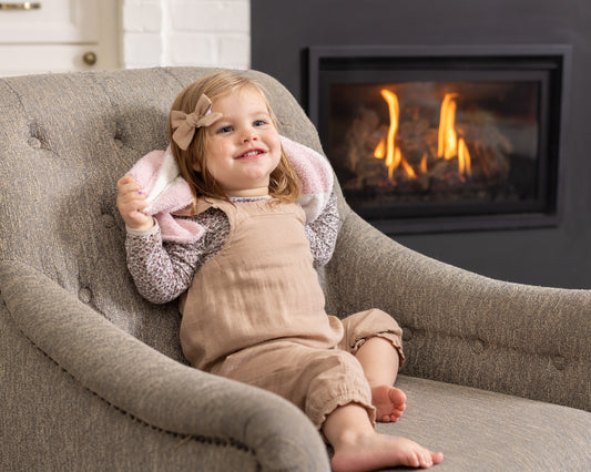 A joyful baby playing with StellaMoon's Luxe Checkered Mini Baby Blanket in Baby Pink, emphasizing its plush texture, ideal size for play, and the comfort it offers in everyday settings.