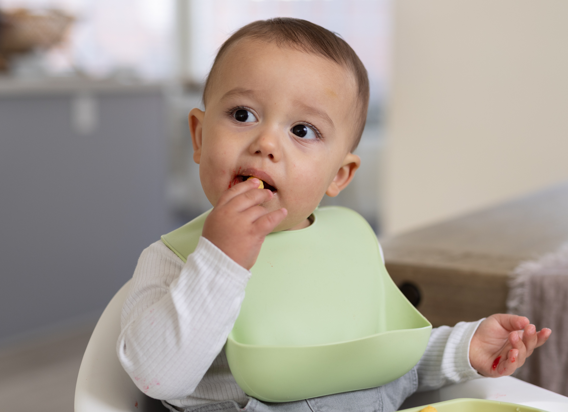 Charming baby wearing the StellaMoon Silicone Baby Bib in Spearmint, all set for a joyous feeding session. The bib's prominent pocket is on full display, highlighting its efficiency in preventing food mishaps, while ensuring a comfortable fit on the little one.