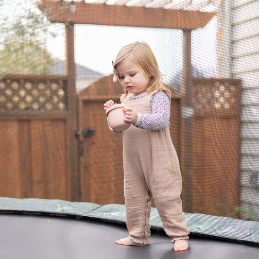 Curious baby holding and examining the StellaMoon Silicone Snack Cup in Blush, emphasizing its safe and baby-friendly design.