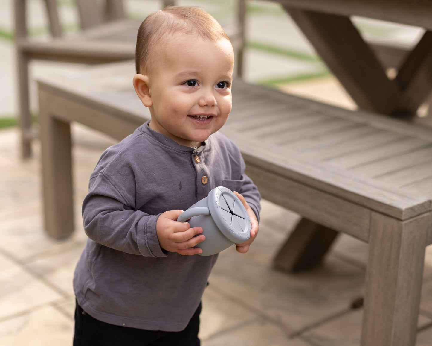 Baby holding StellaMoon Silicone Snack Cup in Stone, showcasing its durable, non-toxic food-grade silicone design.