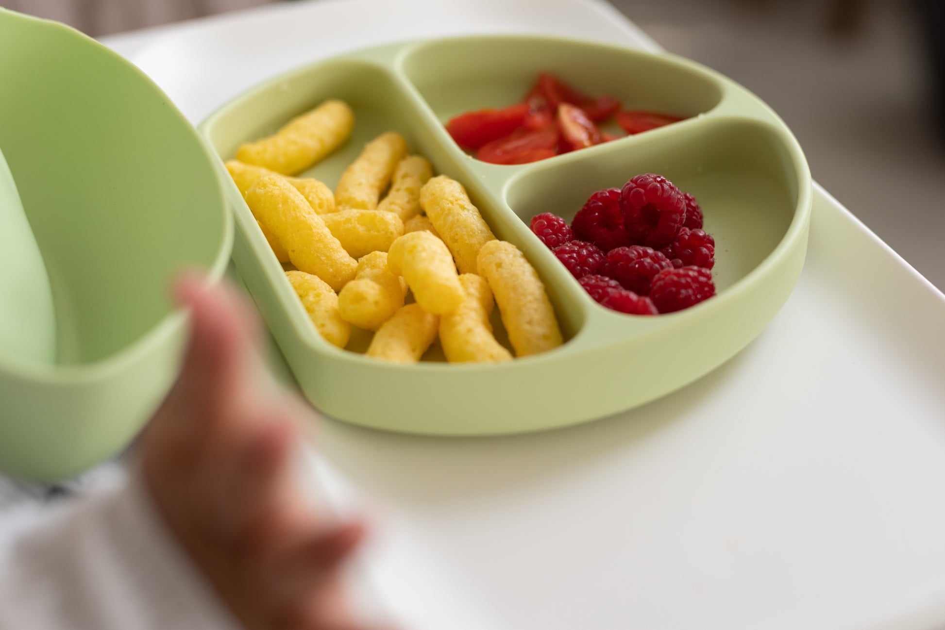 Baby joyfully using the StellaMoon Silicone Suction Plate in Spearmint during mealtime, highlighting its vibrant color, three-section design, and robust suction base for a delightful and mess-free dining experience.